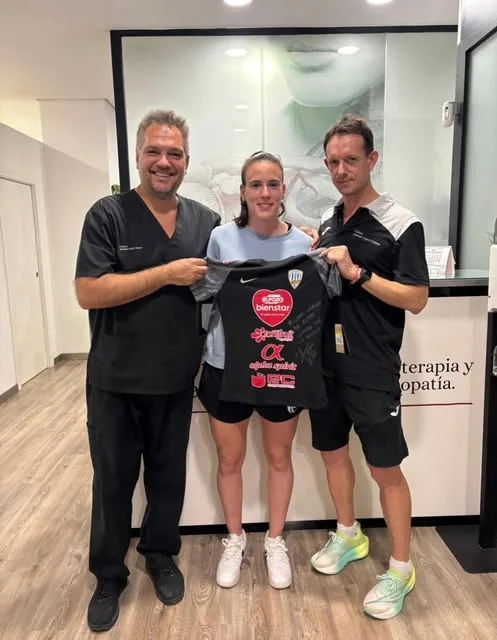 Una futbolista con su camiseta junto a Antonio y otro fisioterapeuta en la recepción